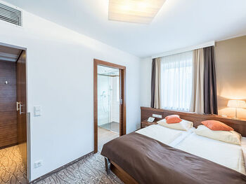 Ein Doppelbett und zwei Türen, eine Führt in das Badezimmer, die andere in den kleinen Flur.