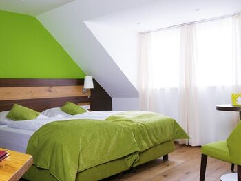 Im Grün gehaltene Hotelzimmer ist ein Doppelbett mit Tisch und Grünen Sessel