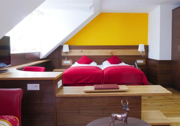 A hotel room in red style. A double bed in the middle of the room.