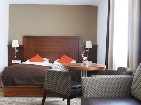 There is a wonderful bed in the middle of the room in front of it there are a couple of chairs and a couch.