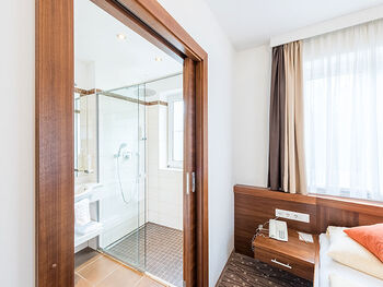 Next to the cozy bed is the bathroom with a large shower.