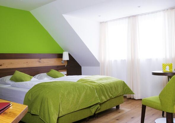 Im Grün gehaltene Hotelzimmer ist ein Doppelbett mit Tisch und Grünen Sessel