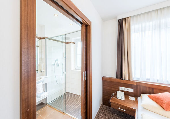 Next to the cozy bed is the bathroom with a large shower.