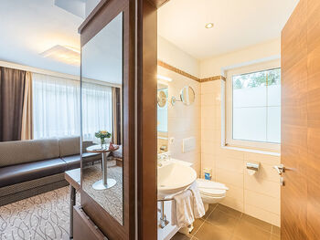 A room, a long couch, a TV and a large bathroom