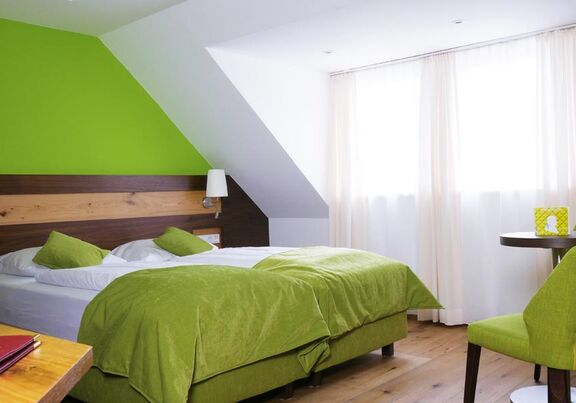 Im Grün gehaltene Hotelzimmer ist ein Doppelbett mit Tisch und Grünen Sessel