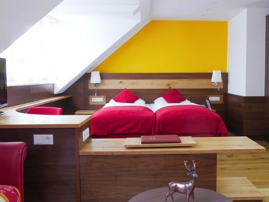 A hotel room in red style. A double bed in the middle of the room.