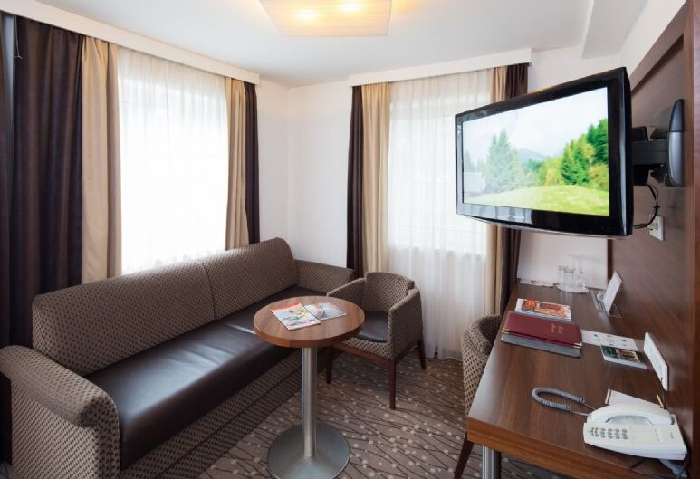 Couch with small round table and a tv on the wall