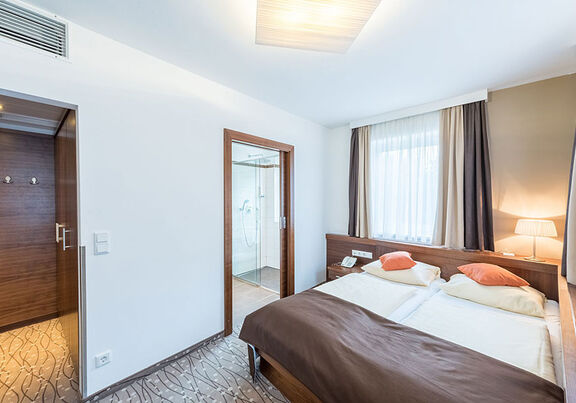 Ein Doppelbett und zwei Türen, eine Führt in das Badezimmer, die andere in den kleinen Flur.