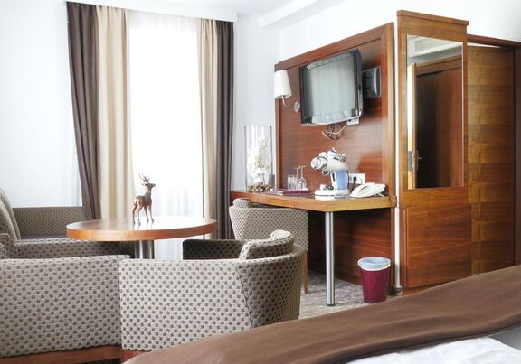 The room has a coffee maker and four different glasses are next to it, above is a large television. Also two very large, comfortable armchairs