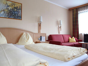 Das gemütliche Zweibettzimmer neben derer eine Couch steht