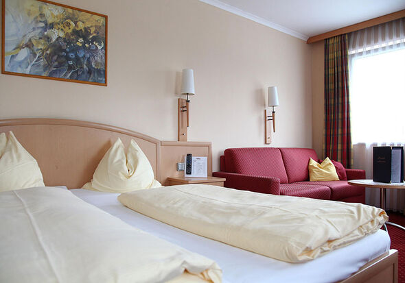 Das gemütliche Zweibettzimmer neben derer eine Couch steht