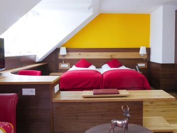 A hotel room in red style. A double bed in the middle of the room.