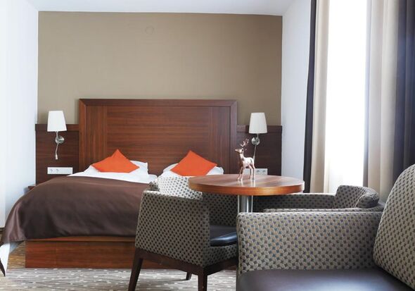 There is a wonderful bed in the middle of the room in front of it there are a couple of chairs and a couch.