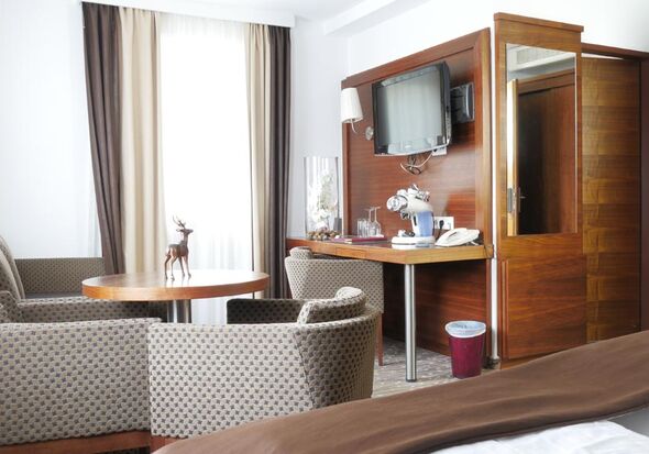 The room has a coffee maker and four different glasses are next to it, above is a large television. Also two very large, comfortable armchairs