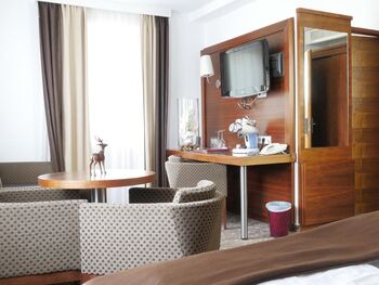 The room has a coffee maker and four different glasses are next to it, above is a large television. Also two very large, comfortable armchairs